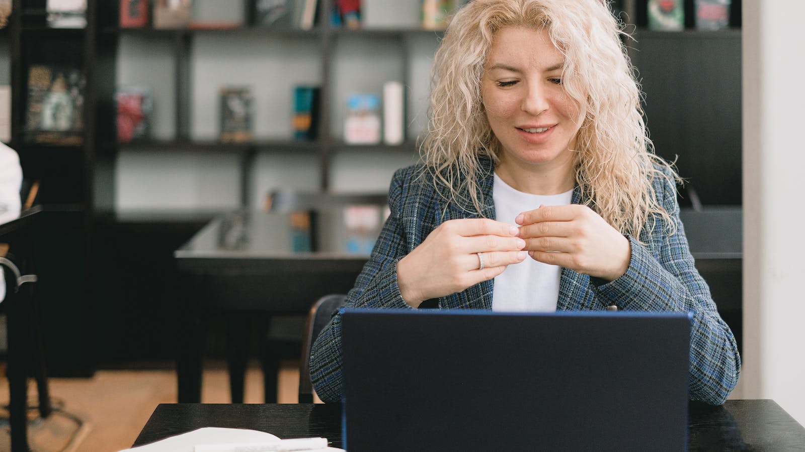 A young woman in business attire reviewing her schedule on a laptop.