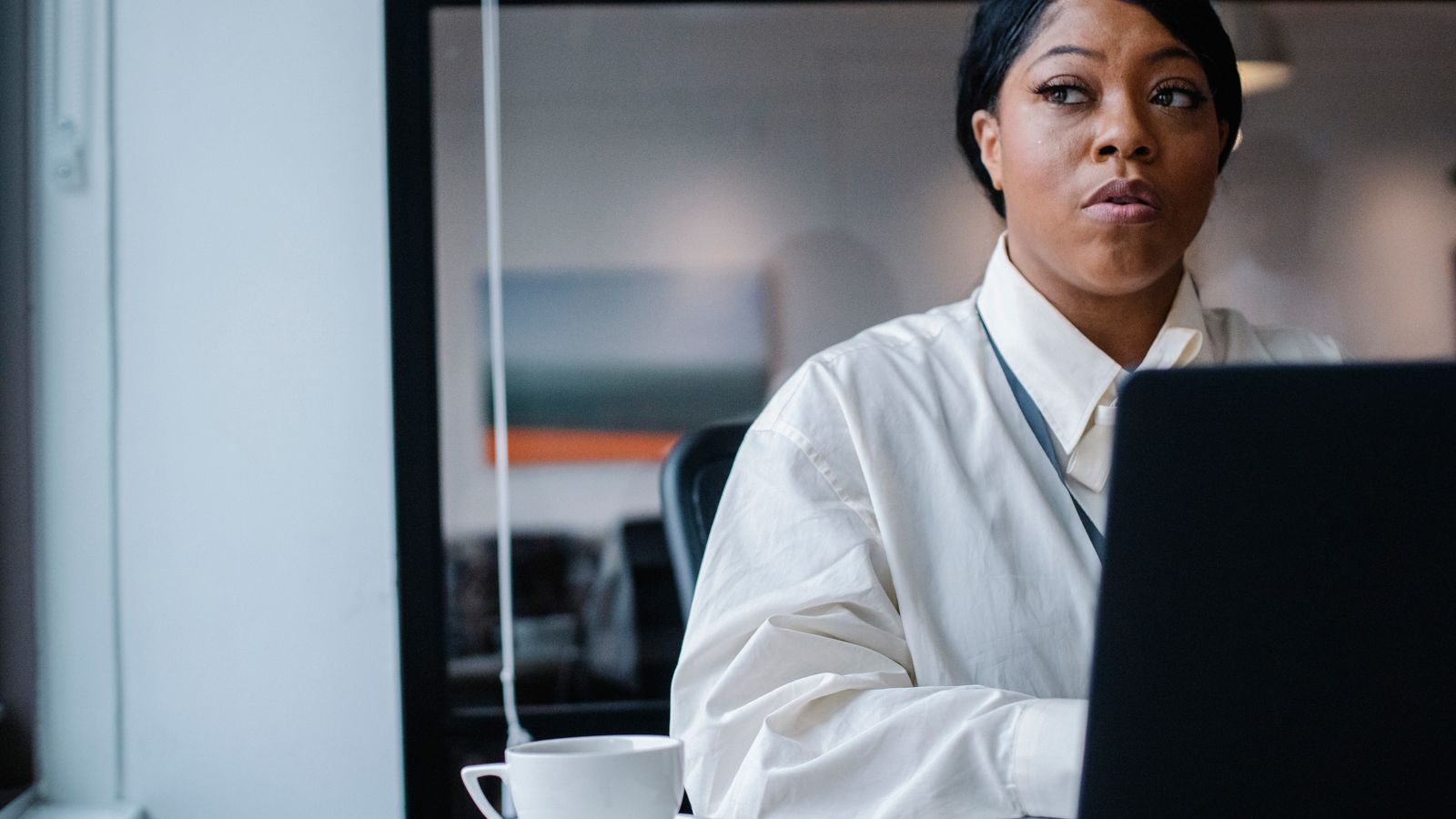 A young woman in business attire reviewing her schedule on a laptop.