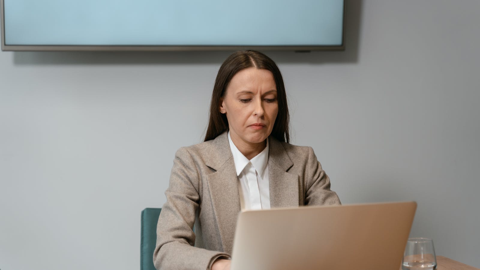 A young woman on a video meeting at her desk with headphones on.