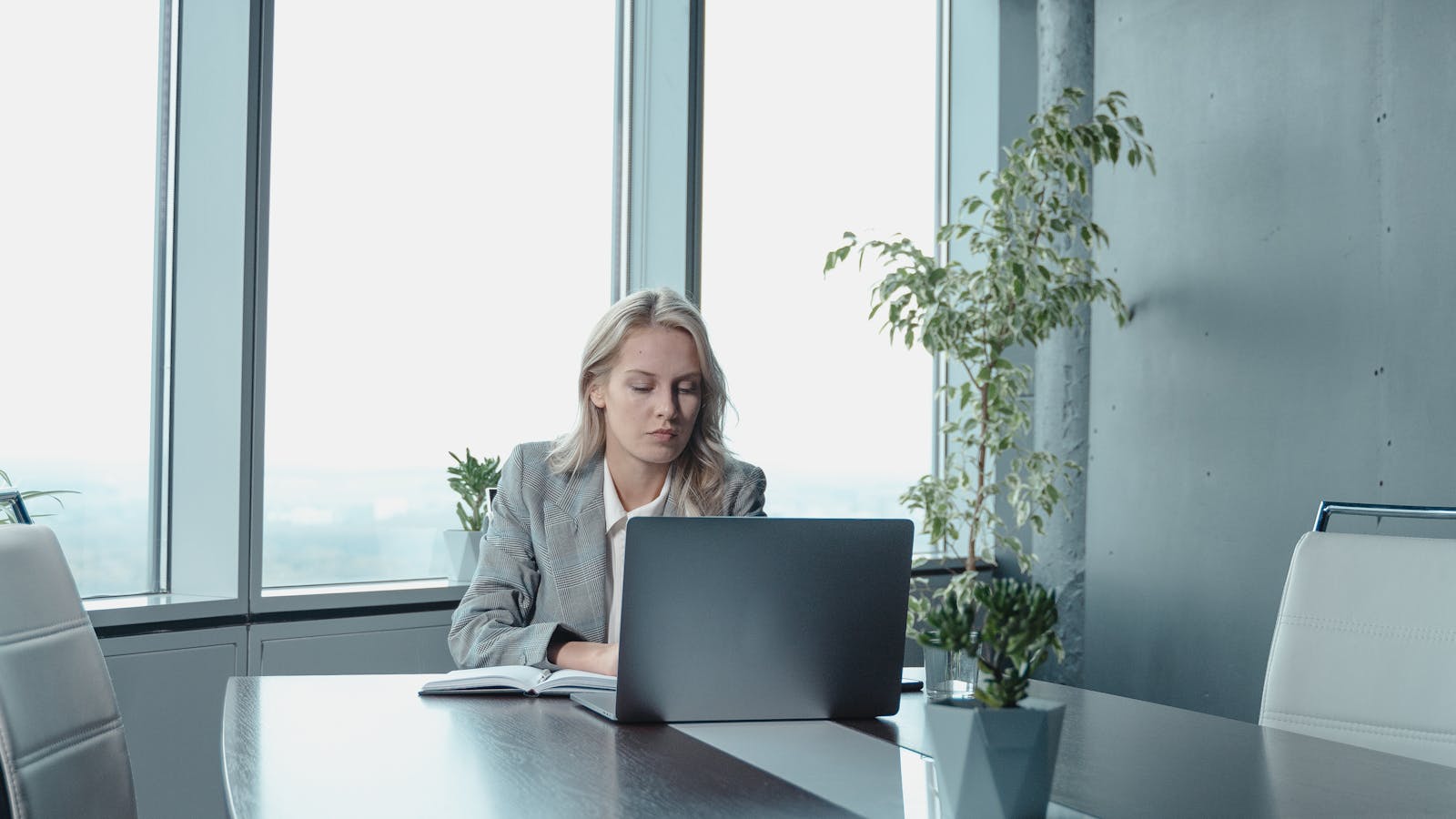 A young woman on a video meeting at her desk with headphones on.