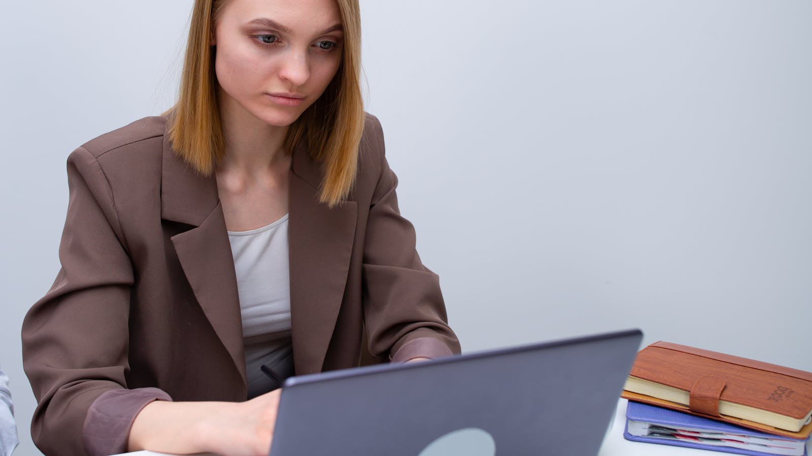 A young woman in business attire reviewing her schedule on a laptop.