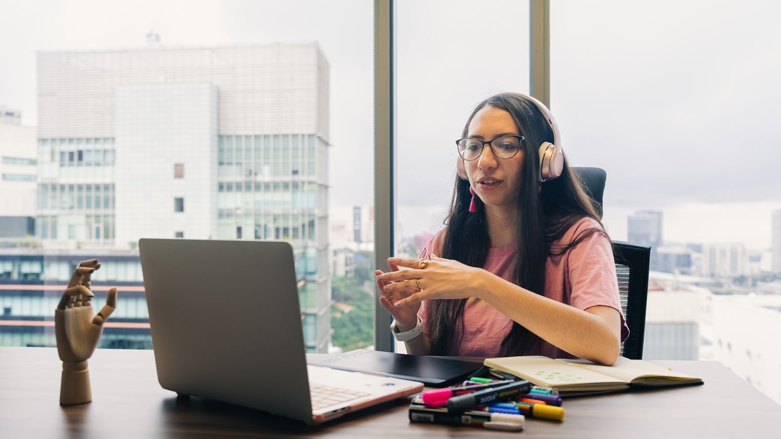 A young woman working on a laptop in a busy open plan office.