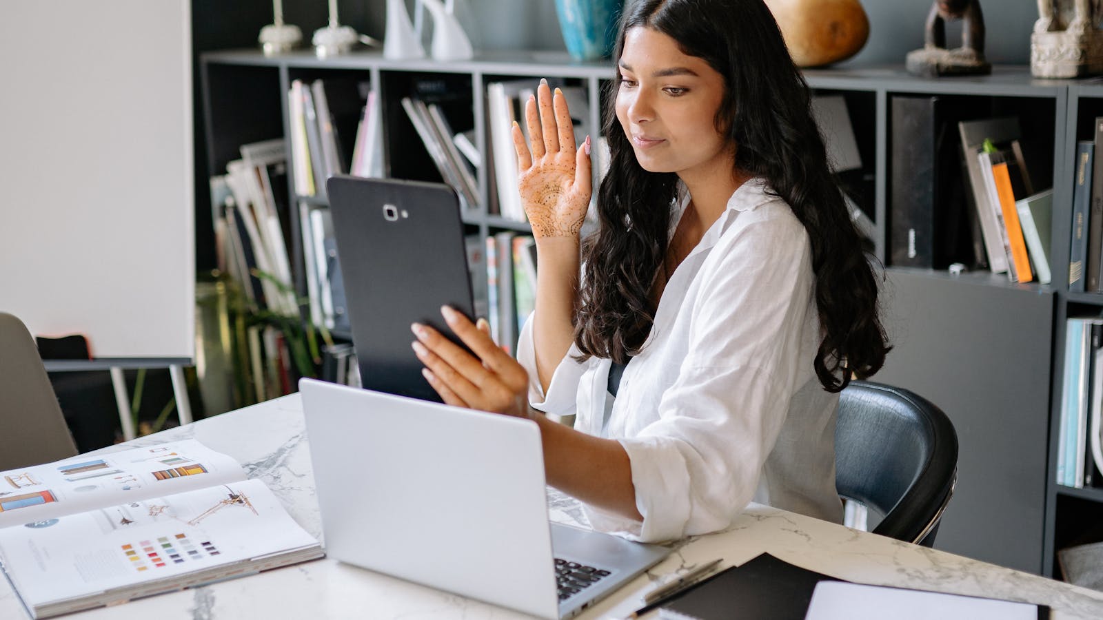 A young woman smiling during an online meeting at her workspace.